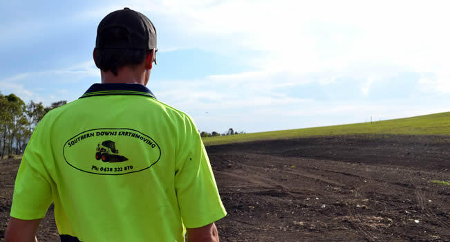back of man in hi-vis shirt with business name and illustration of bobcat